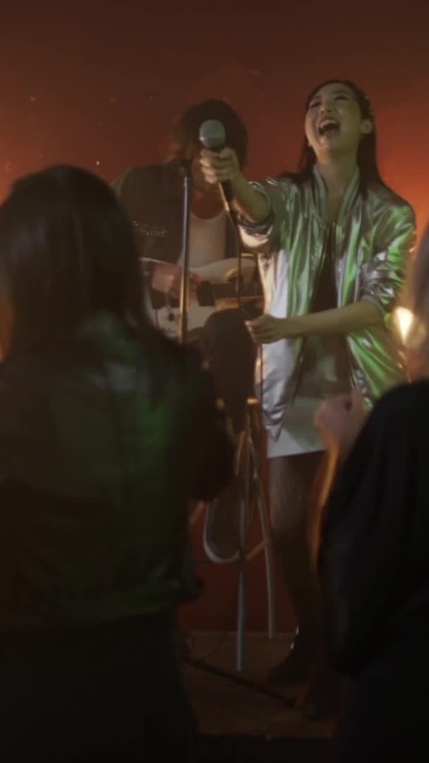 Friends raise glasses and a band plays at a small late-night venue
